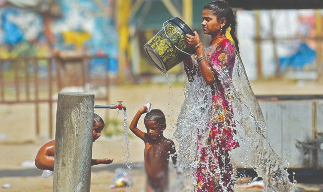 People cool off at a public water fountain during the heat in India