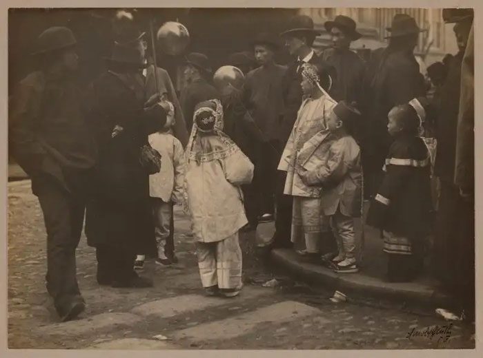 Children surrounding a balloon vendor, 1900.