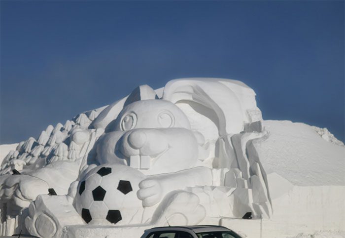 A snow sculpture of a rabbit holding a soccer ball in Harbin, China.