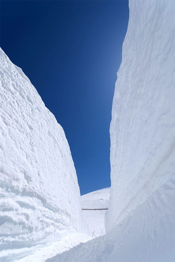 Snow walls towering on both sides of the road.