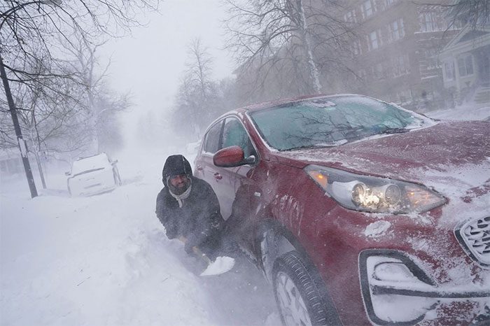 A man tries to dig out snow around his car.