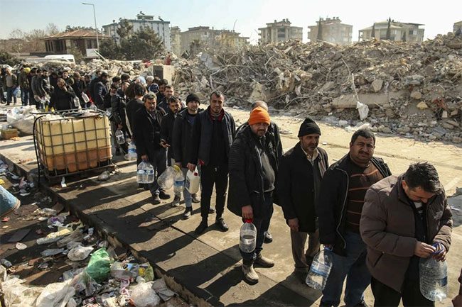 People queueing for water near collapsed buildings in Kahramanmaraş, Turkey