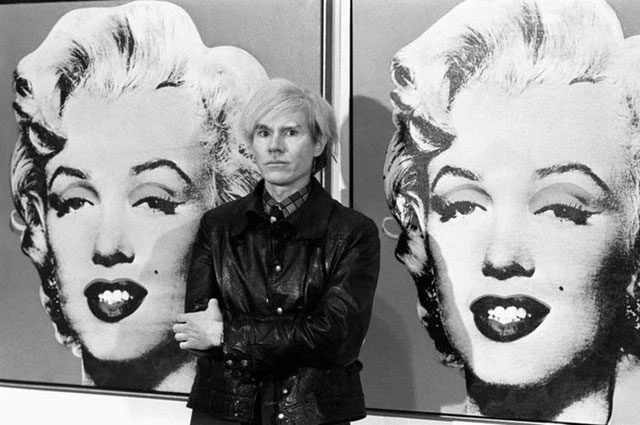 Artist Andy Warhol with his works on Marilyn Monroe.
