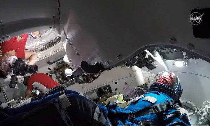 NASA astronaut Kjell Lindgren takes a photo of the Rosie the Rocketeer dummy while Robert Hines works nearby. The two astronauts entered the Starliner for the first time on May 21