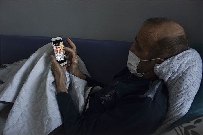 The man can only watch his loved ones from afar, through glass or on the phone.