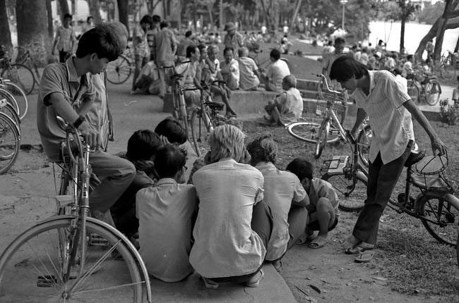 Group of men gathered around a chess table by Hoan Kiem Lake.