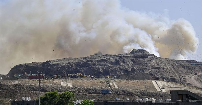 Thick smoke rising straight into the sky from the Ghazipur landfill, Delhi, India.