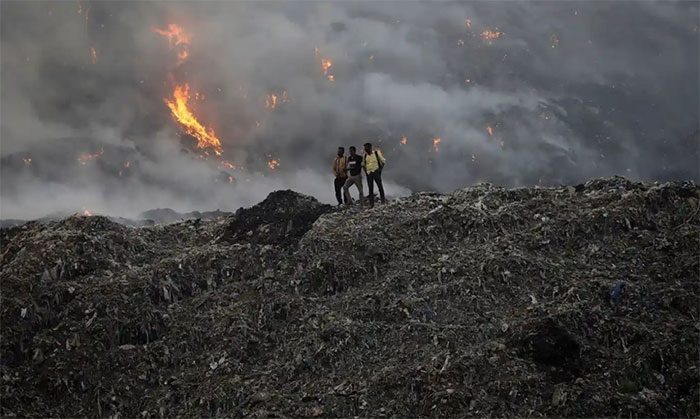 Residents standing at the burning Ghazipur landfill in Delhi, India.