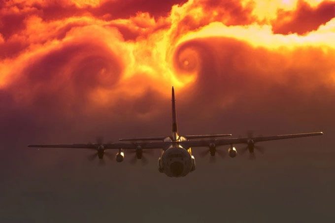 A passenger airplane flying above a cloud layer during sunset.