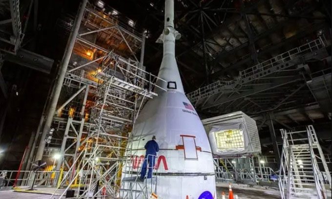 Engineers dismantling the support structure around the spacecraft.