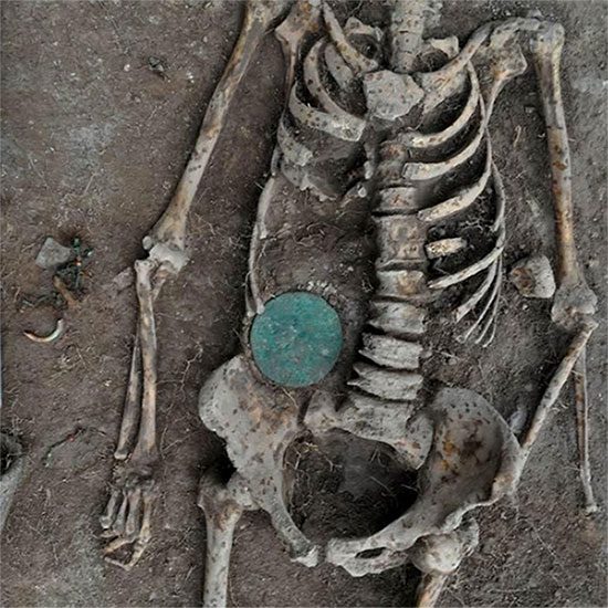 Bone amulet beside the right side of the woman (left side of the photo)