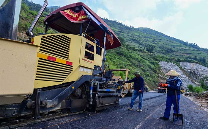 Dozens of workers are completing about 100m of the access road to the Móng Sến Bridge.