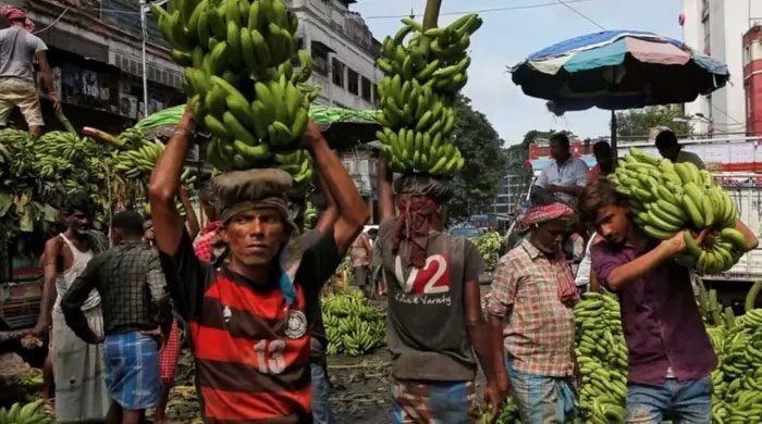 Workers unloading bananas from a truck at a market in Kolkata.