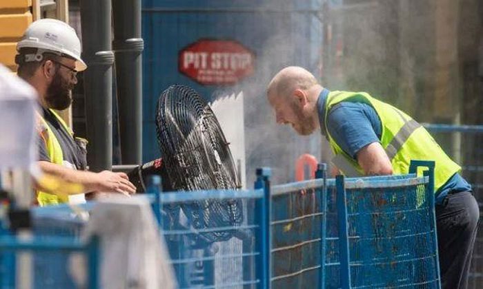 A construction worker uses a large fan to cool down in Canada