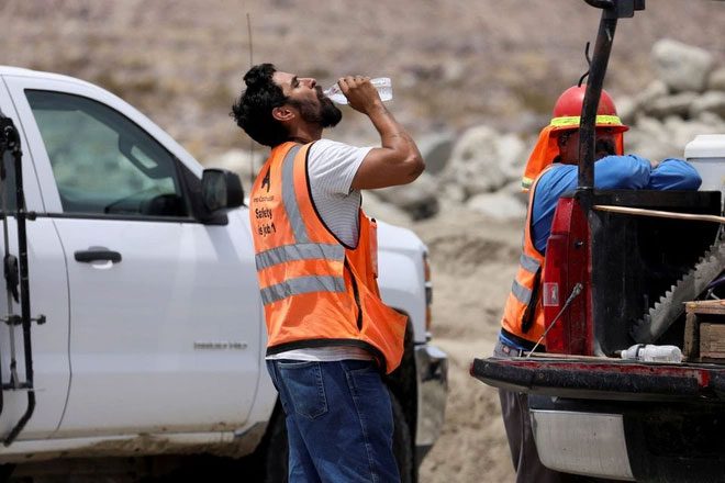A construction worker drinks water in the sweltering heat in Palm Springs, California, USA