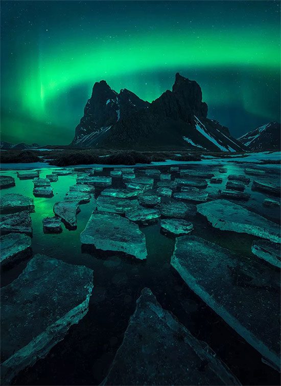 Auroras reflecting on a frozen lake in Iceland.