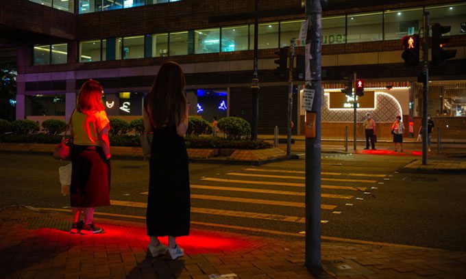 Red LED lights illuminating a crosswalk in Hong Kong to alert pedestrians to stop.