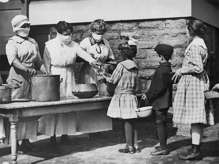 Children from underprivileged families lining up for food served by volunteers
