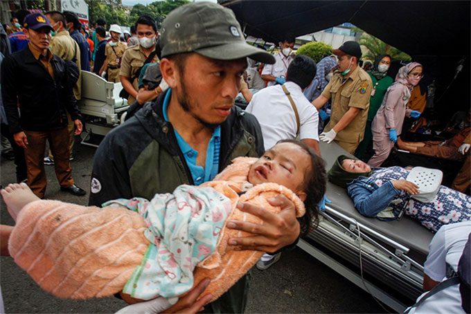 An injured child being carried by their father to a treatment facility in Cianjur, Indonesia, on November 21.