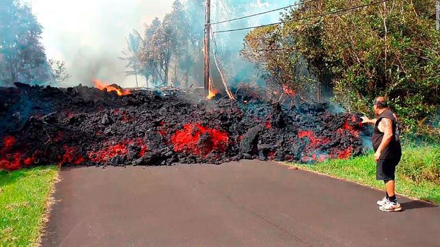 Humans struggle to stop the flow of lava.