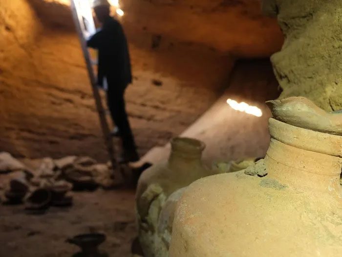 An archaeologist descending into the cave using a ladder.