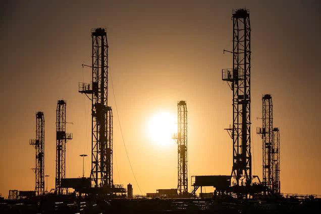 The sun rises over oil rigs being stored on February 6, 2021