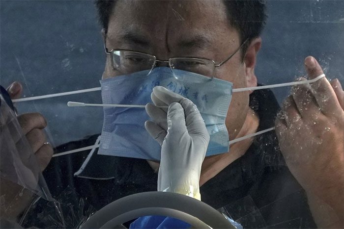 A man removes his mask to test for the SARS-CoV-2 virus in Beijing, China.