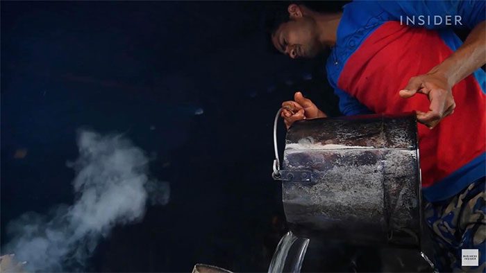 Workers prepare copper barrels, pouring in 80 liters of water.