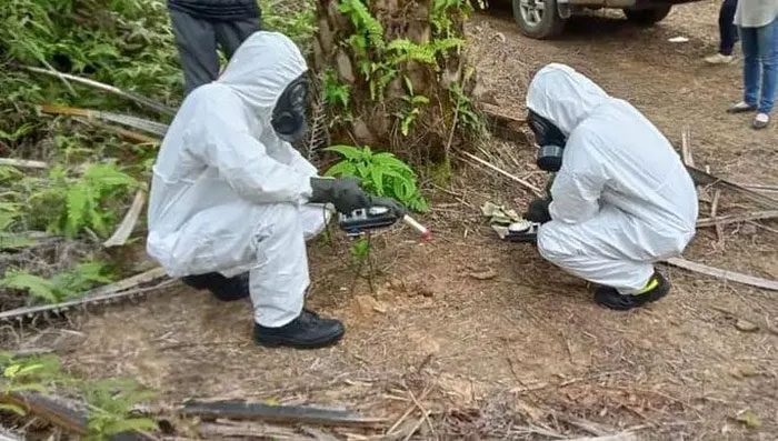 Personnel in protective gear inspecting another piece of debris in Sarawak, Malaysia