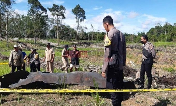 Indonesian police inspect a piece of rocket core debris in Pengadang village