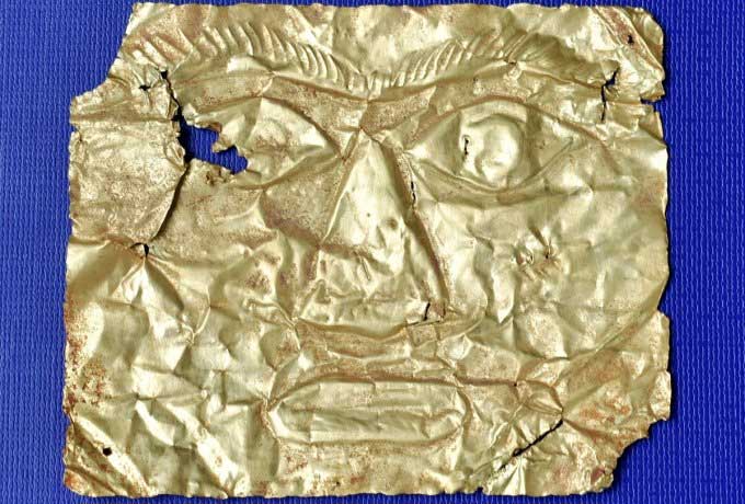 The third gold mask with a complete human face design.