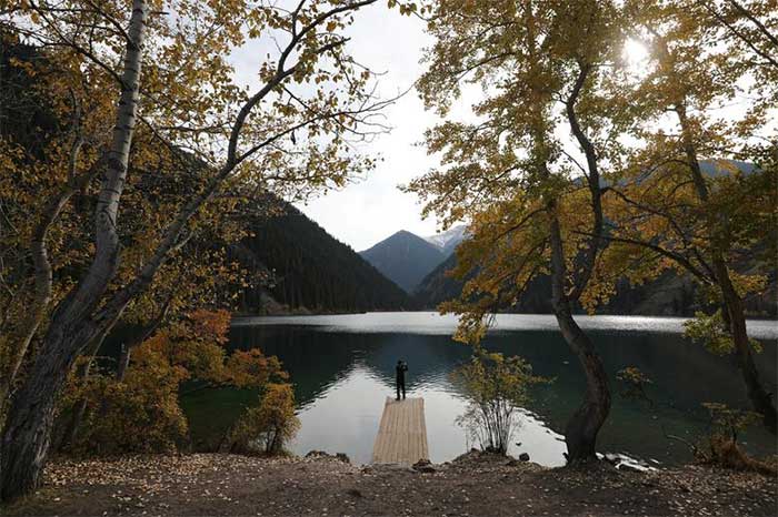 A man photographing autumn at Kolsai Lake in Almaty region, Kazakhstan on September 30, 2020