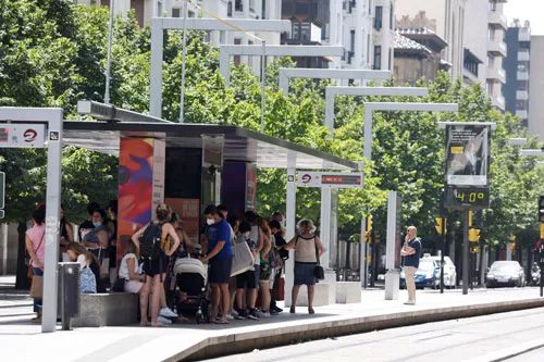 People gather waiting for the tram while the outdoor thermometer reads 40 degrees Celsius in Zaragoza