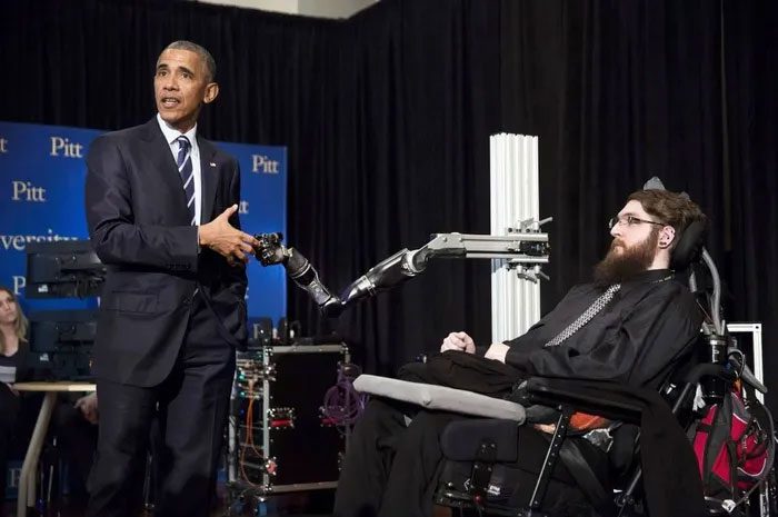 Nathan Copeland controlling a robotic arm to shake hands with former President Obama.