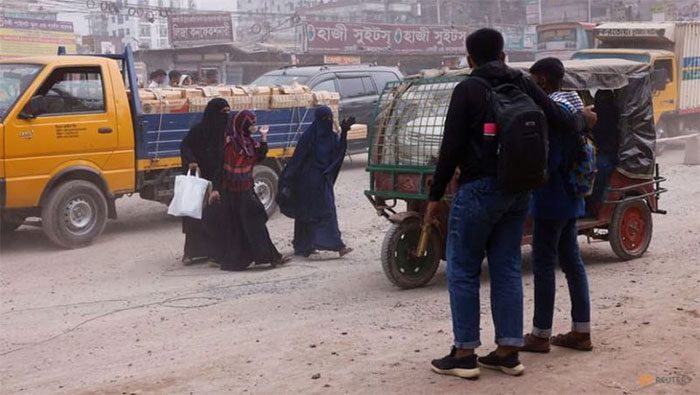 Bangladeshi residents crossing a dusty road due to severe air pollution