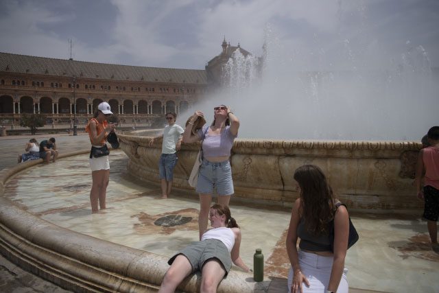 People cool off at a fountain during the heatwave in Seville, Spain.