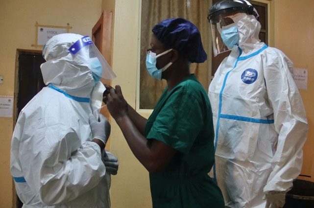 Helping colleagues adjust protective gear in Nigeria.