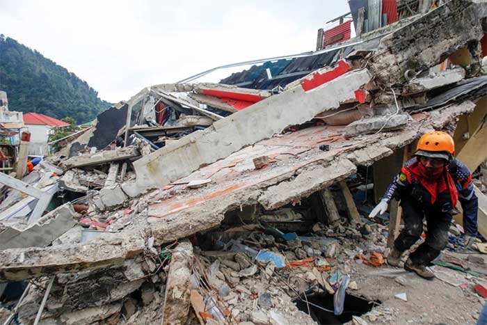 A rescue worker navigates through the rubble of collapsed buildings in Indonesia.