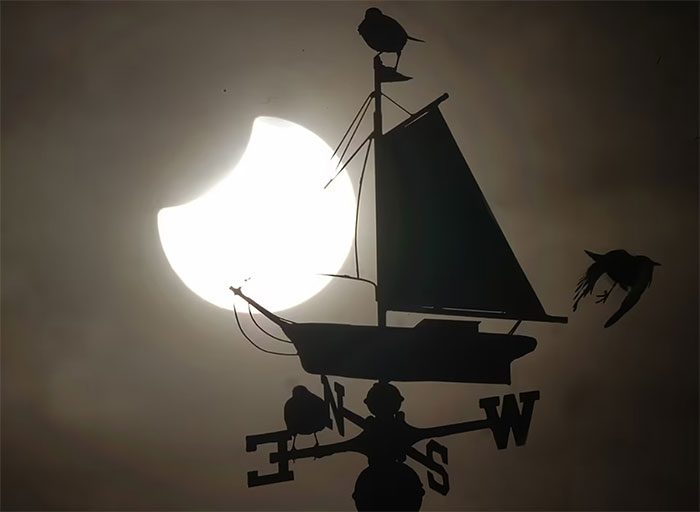 Partial solar eclipse behind the sailing boat symbol atop the Cullercoats Watch House public building