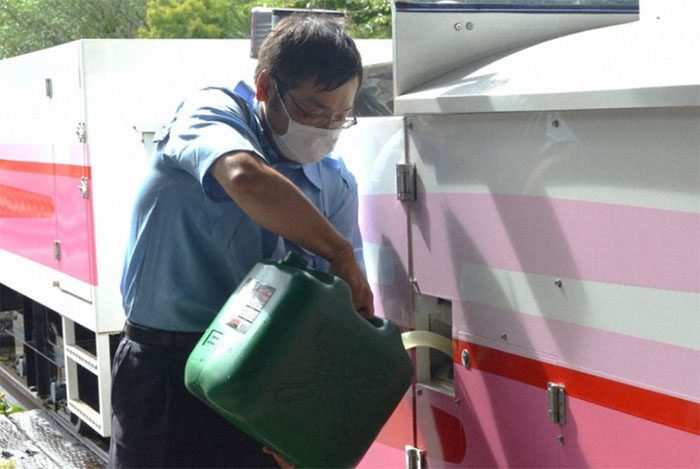 Staff pouring biodiesel made from ramen soup into the train