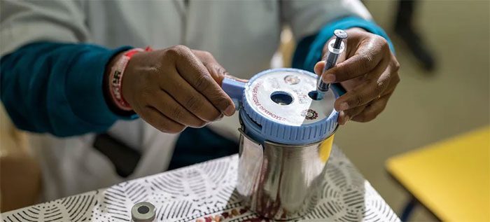 Healthcare workers disposing of used Covid-19 vaccine syringes into a container.