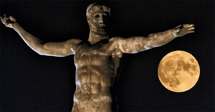 The moon next to the statue of the Greek god Poseidon in the ancient city of Corinth near Athens.