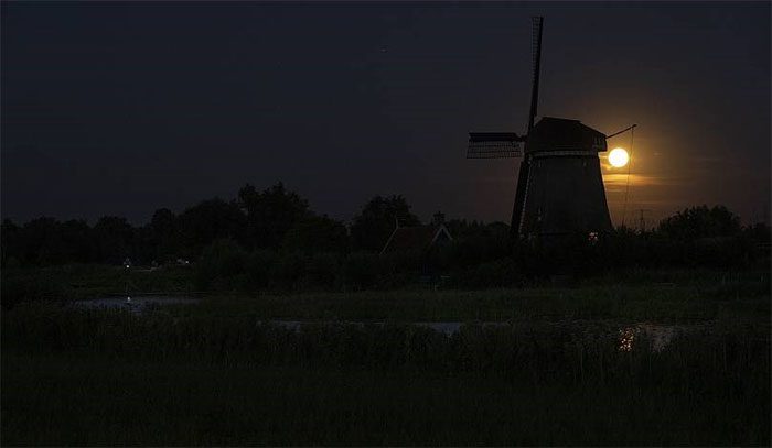 The supermoon peeking behind a windmill in Oostzaan, Netherlands.