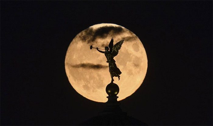 The 'Sturgeon' moon rises behind the dome of the Academy of Fine Arts with the angel 'Fama'.