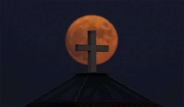 The supermoon rises behind the cross on the dome of St. Maron Church in Anthoupolis, the suburbs of Nicosia, Cyprus.