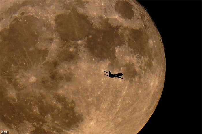 A small airplane in front of the supermoon.