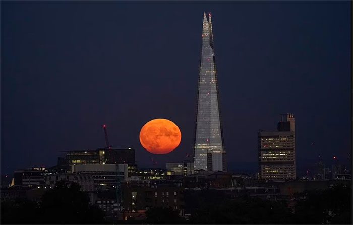 The Sturgeon Moon rises behind The Shard building in London, England.