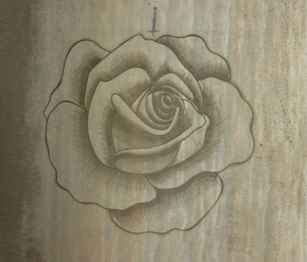 Manuel Frolich uses dark sand to create his painting