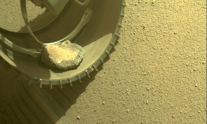 Hazcams on Perseverance capturing the rock stuck in the rover's wheel.
