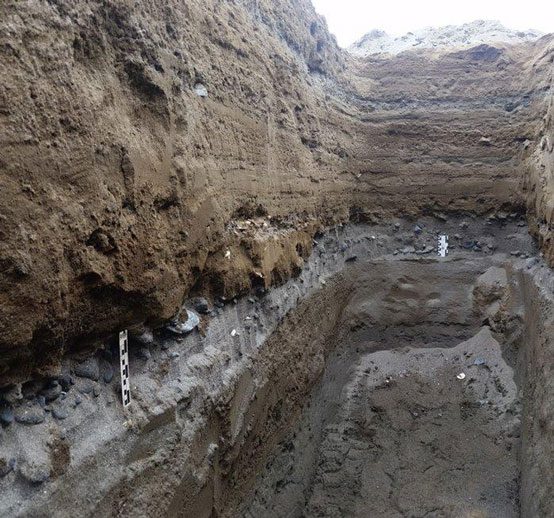 A deep hole excavated by researchers revealing remnants of human life disrupted by a disaster